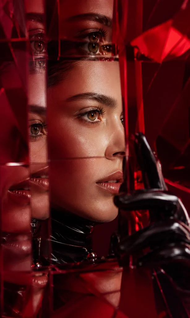 Woman rotating a red optical prism to bring repeated reflections of her face back into alignment